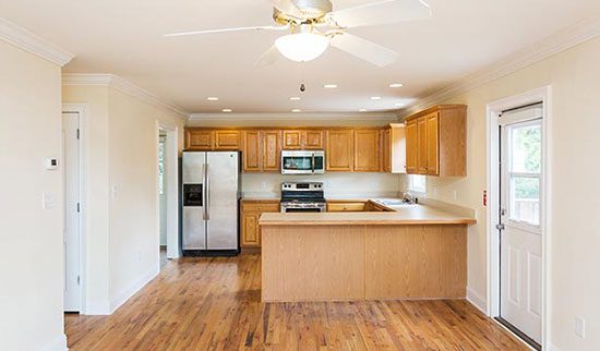 Kitchen with silver and black appliances, light wooden cabinets and snack bar.