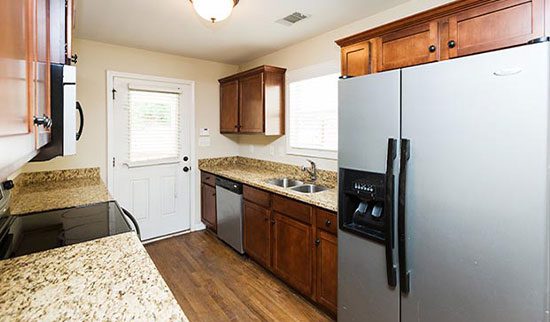 Kitchen with large, stainless steel 2-door fridge and dark wood cabinets.