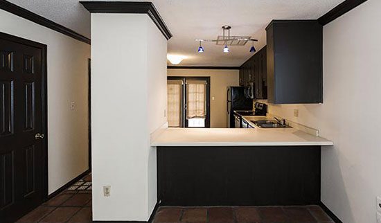 Kitchen with white walls, black accent trim and cabinets and snack bar.