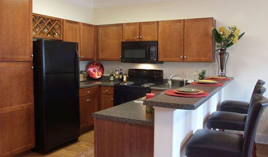 Kitchen with black appliances, dark wood cabinets and bar with stools