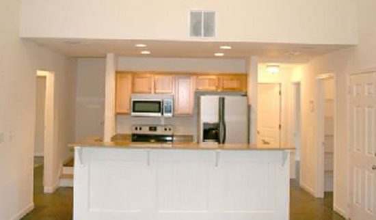 Kitchen with silver appliances, light wooden cabinets and snack bar.