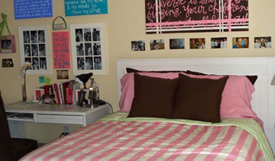 Comfy bed with a pink striped comforter, and images up on the wall behind it