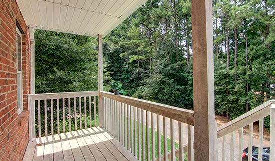 View from the porch with white guard rails and tree's beyond.