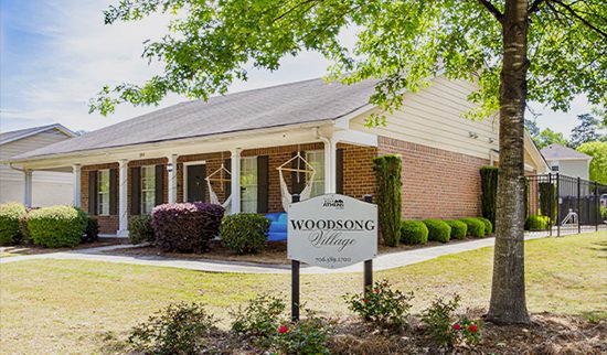 A view of a red brick building in Woodsong Village, featuring the community signage.